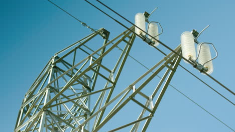 primer plano de aisladores en pilón eléctrico, fondo de cielo azul