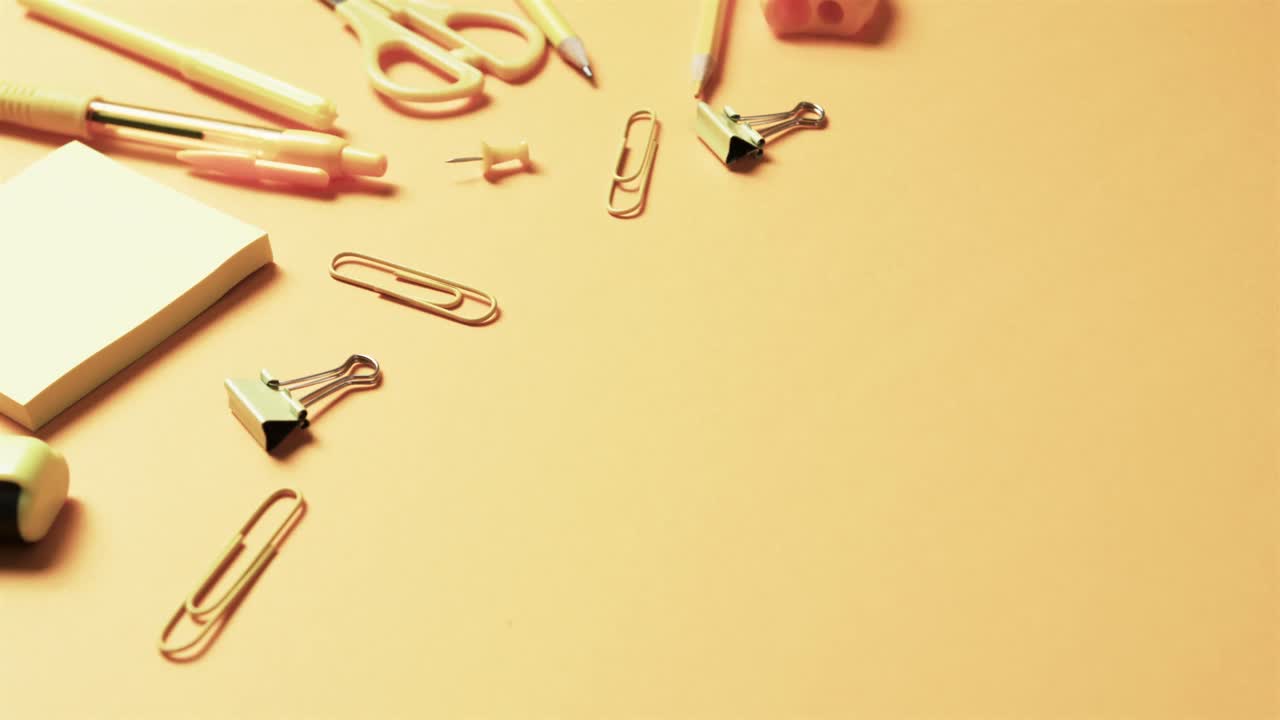 close up de papelería escolar con espacio de copia en fondo naranja, en cámara lenta