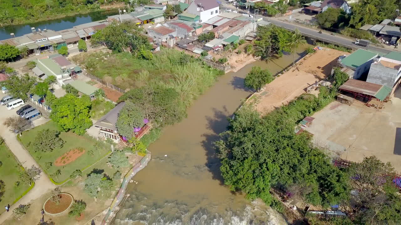 Drone footage of river and Elephant waterfall on stones in Vietnam, Dalat. Village and road with pond and trees and nature.