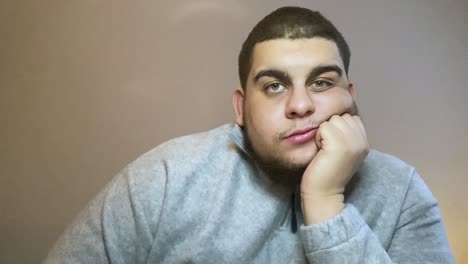 young university student visibly bored whilst looking directly into camera during remote lecture