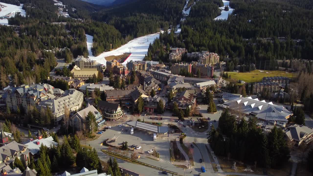 Whistler resort town with bus loop and mountain backdrop, aerial view