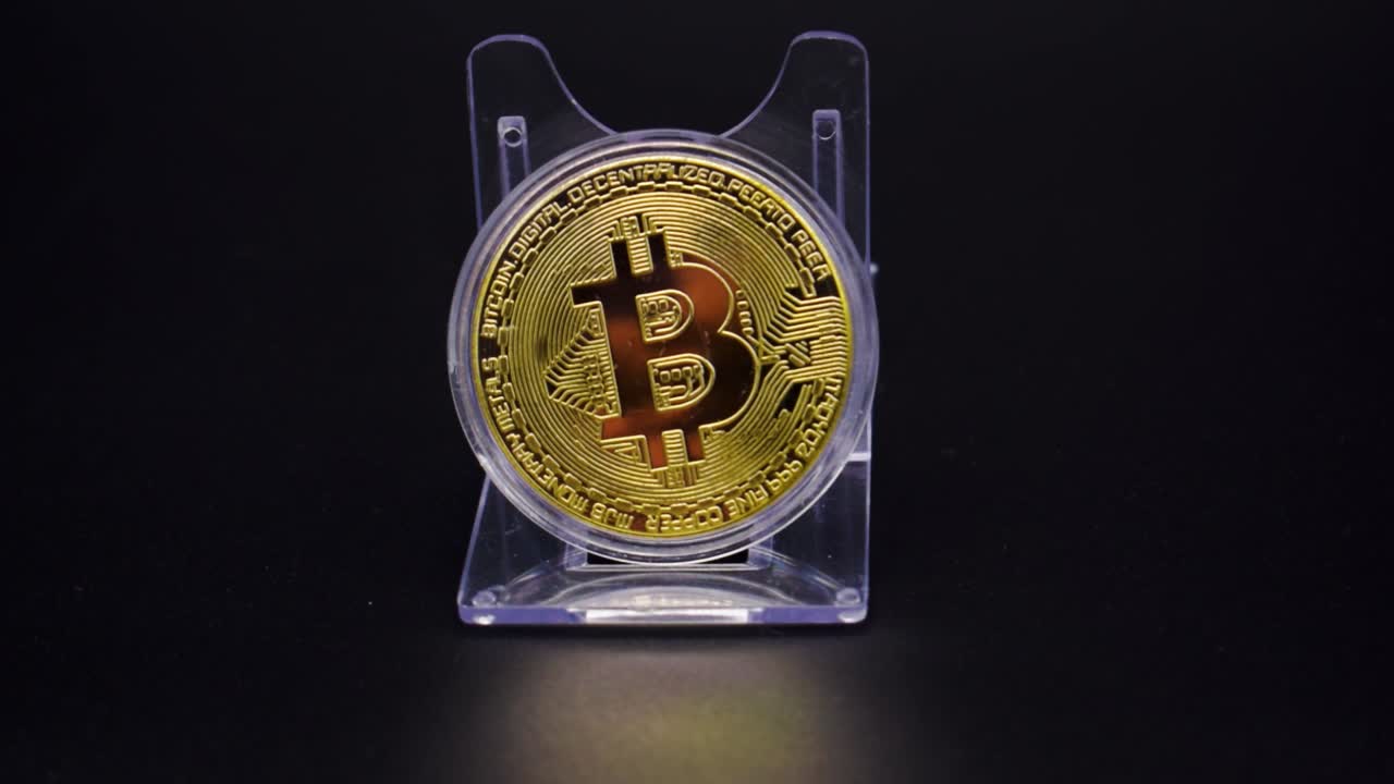 Close Up Of Physical Golden Bitcoin In Plastic Shelf On A Black Background. - slow motion, pan shot.