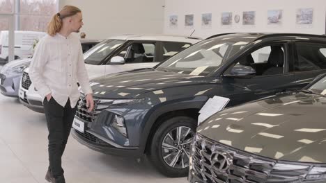 young man at car showroom choosing a new car to buy.