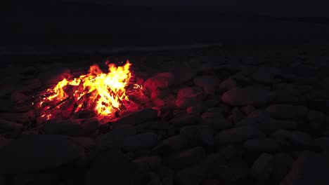 medium shot of a fire on a rocky beach at night time