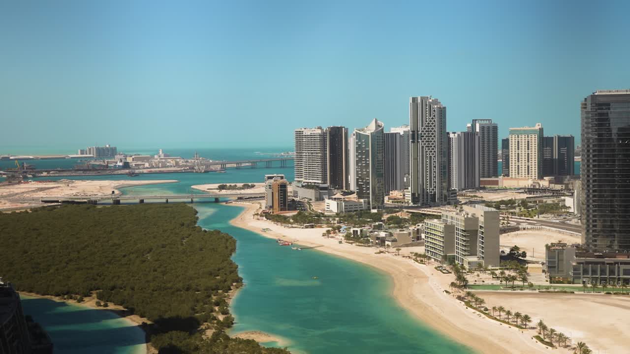 Looking out a skyscraper window on Al Reem Island, Abu Dhabi, United Arab Emirates at the beach, sea, mangrove forest, and city skyline