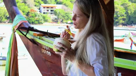 woman enjoying a coconut drink by the beach