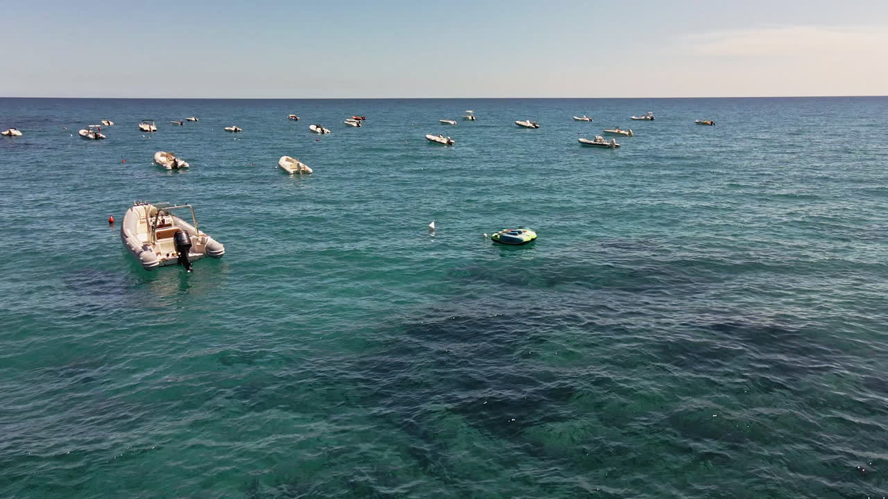vista cuesta arriba sobre el mar azul con un grupo de barcos amarrados con boyas en alta mar en cerdeña, italia - toma amplia de aviones no tripulados en cámara lenta