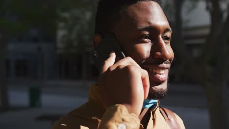 African-american-businessman-with-face-mask-talking-on-smartphone