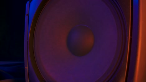 bass audio speaker during party with colourful lights. speakers playing and membranes vibrating to the rhythm electronic music. close up. slow motion