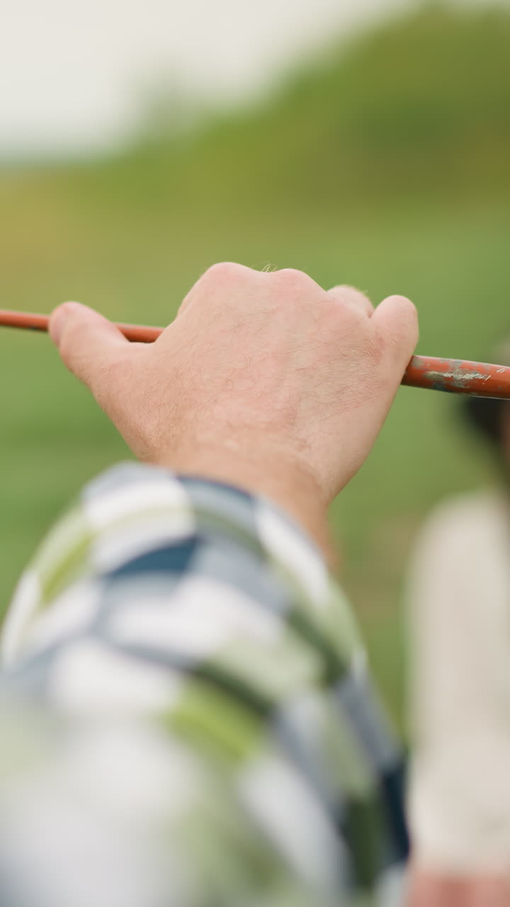 Focused shot of a painter's hand holding a small brush against a soft green backdrop, capturing a moment of artistic precision