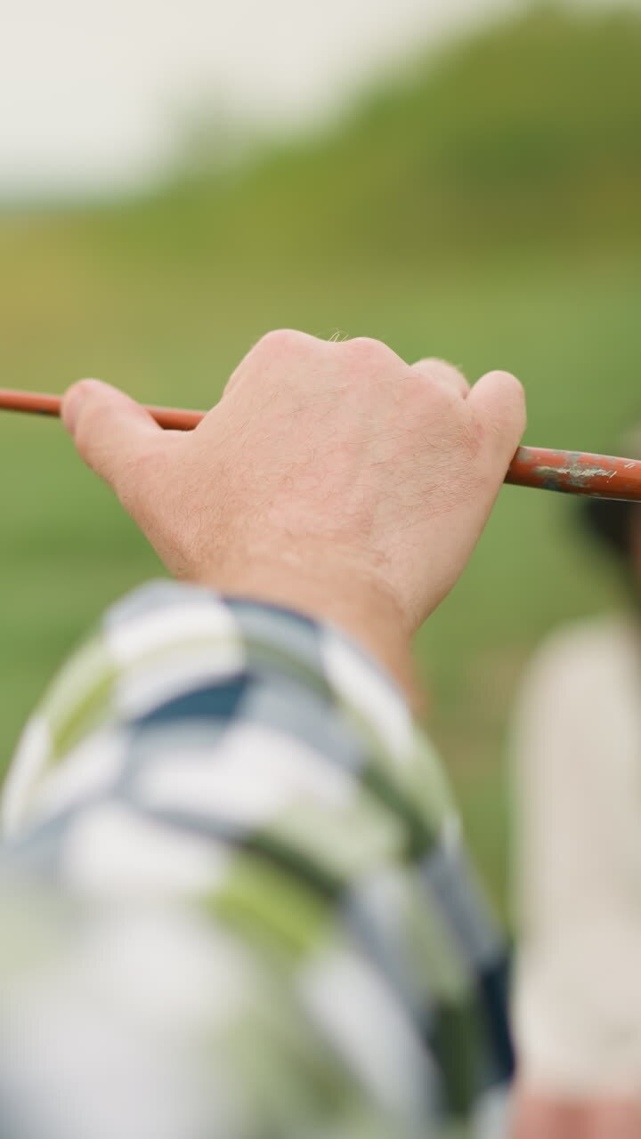 Focused shot of a painter's hand holding a small brush against a soft green backdrop, capturing a moment of artistic precision
