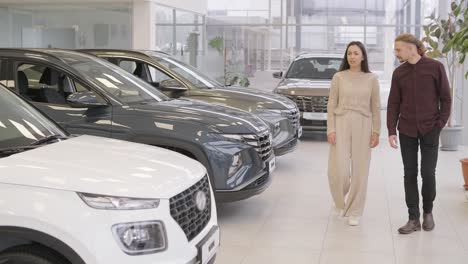 beautiful young couple at car showroom choosing a new car to buy.