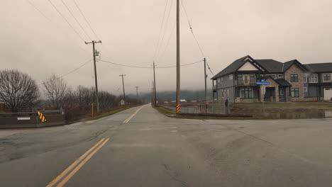 driving through a rain soaked rural area with water pooling around large homestead