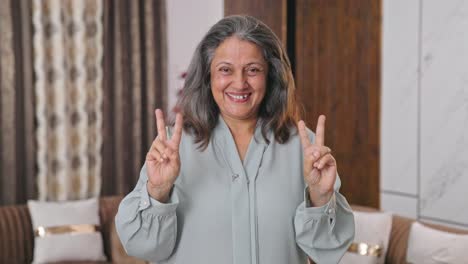 mujer india moderna feliz mostrando el signo de la victoria