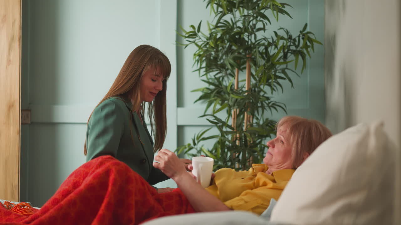 돌보는 여자 는 고령자 어머니 에게 약 과 물 이 들어 있는 컵 을 준다