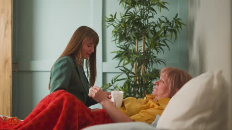 caring woman gives pill and cup with water to senior mother