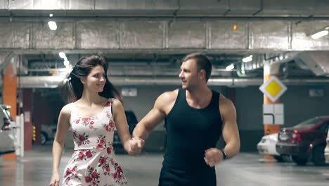 couple in summer dressing runs on underground parking lot