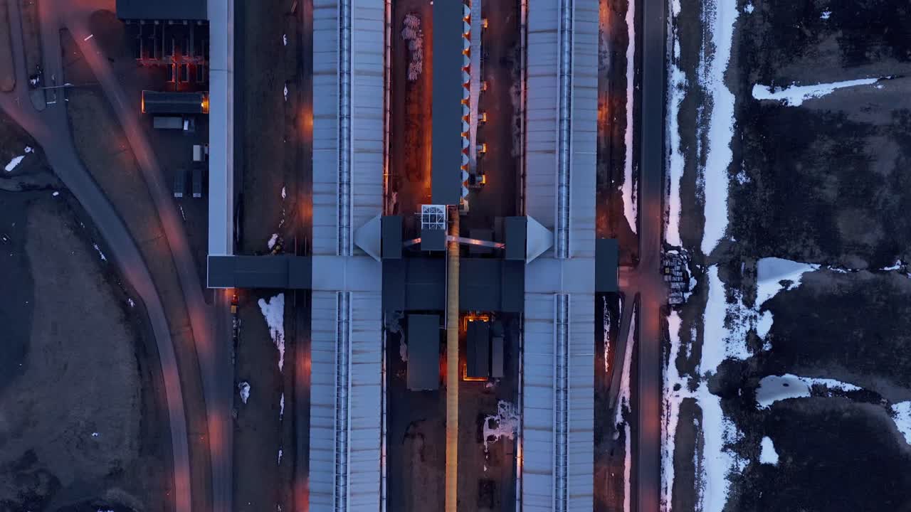 de arriba hacia abajo sobre un largo edificio de producción de aluminio con luces nocturnas encendidas, antena