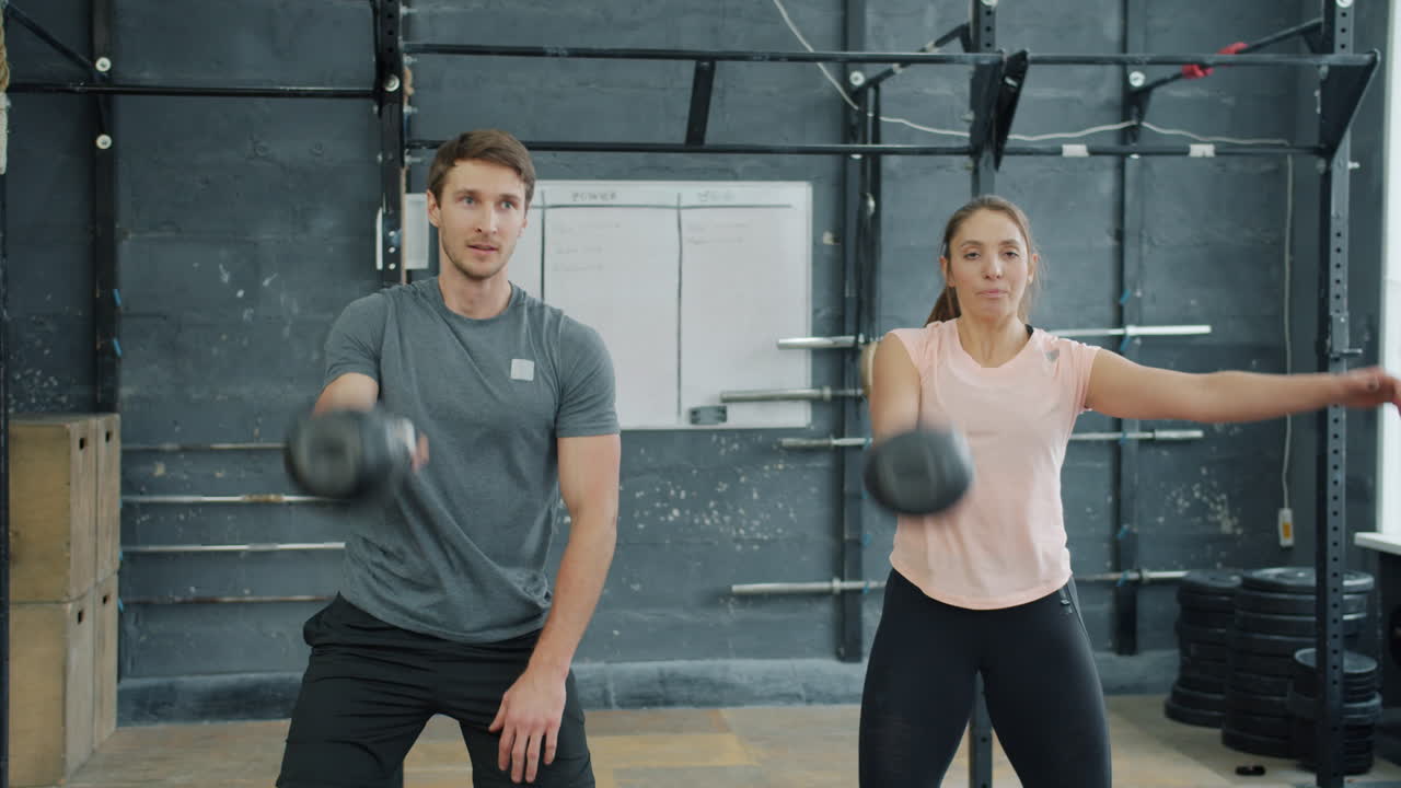 Couple working out with kettlebells in a gym