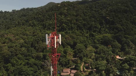 aerial drone slow clockwise orbit shot of telecommunications tower on a tropical island in thailand with jungle behind