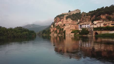 Vuelo-Con-Drones-Sobre-El-Río-Ebro,-Vista-Del-Pueblo-Y-El-Castillo-De-Miravet