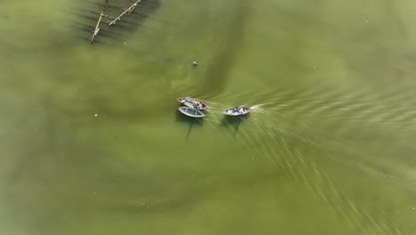 drone view a wooden boat is pulling another one on quan tuong river, nha trang city, khanh hoa province, central vietnam