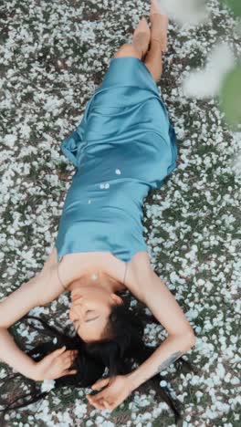 woman in a blue satin dress among cherry blossoms