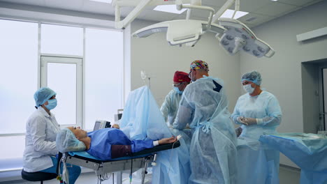 surgical team performing vascular operation in modern surgical room. conscious female patient talks to the doctors operating her.