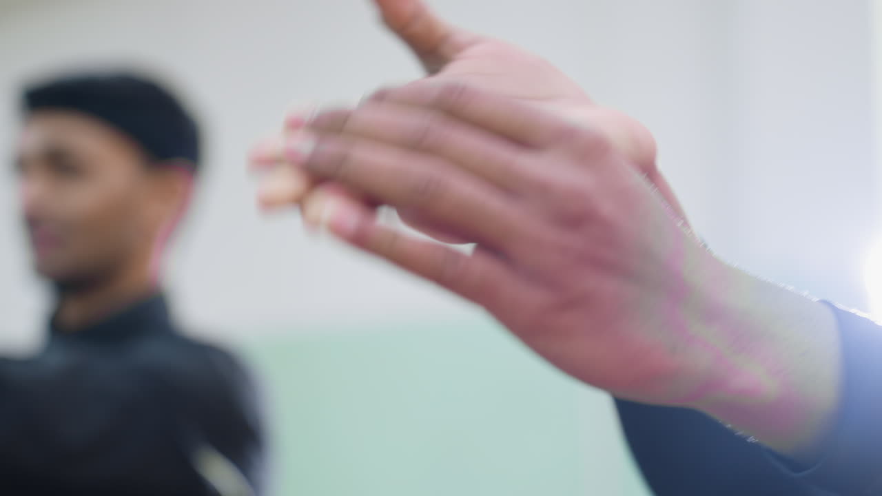 Close up of men stretching hands during indoor workout session focusing on wrist flexibility, control, muscle preparation, and concentration before sports activity with blurred training background