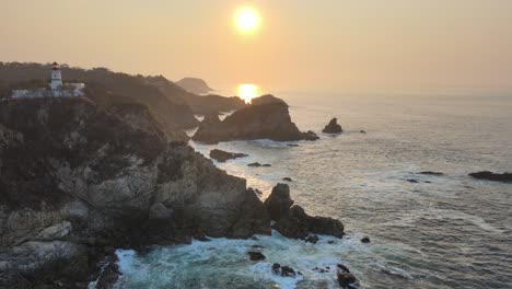 tire hacia adelante sobre la costa rocosa en un amanecer brumoso, con vista a un faro en la costa de oaxaca