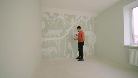 the artist is decorating walls by drawings in the children's room. art painting of the walls in the new house. repair works.