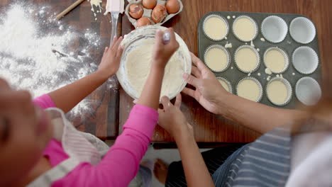 overhead of biracial mother and daughter baking, mixing cake mix, slow motion