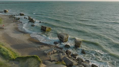 beautiful aerial establishing view of karosta concrete coast fortification ruins, sunny summer evening, golden hour light, stormy waves at baltic sea, slow motion drone shot moving forward