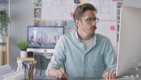 arquitecto masculino en la oficina trabajando en una computadora de escritorio usando una tableta gráfica