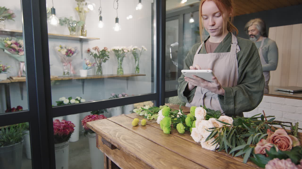Fiorista donna che usa un tablet digitale al lavoro