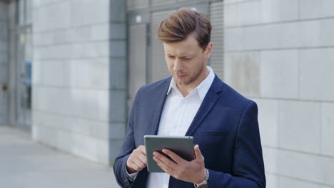 Businessman using digital tablet in city. Professional browsing internet on pad