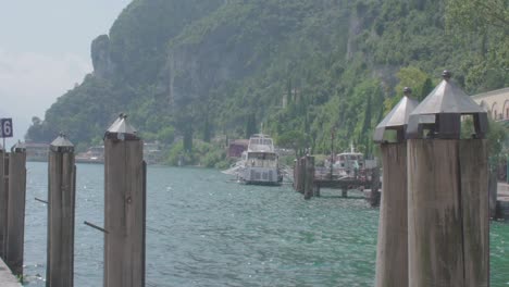 Beautiful-lakeview-at-the-lake-garda-in-Riva-Del-Garda-Italy-with-a-public-transportation-ferry-and-mountains-in-the-background