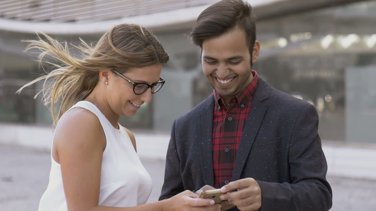 jóvenes sonrientes usando teléfonos celulares al aire libre