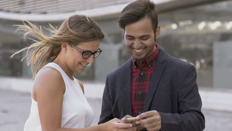 Smiling-young-people-using-cell-phones-outdoor