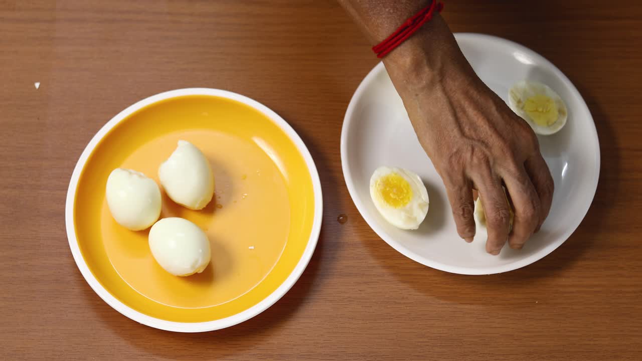 A woman takes boiled eggs from a yellow plate and decorates a white plate