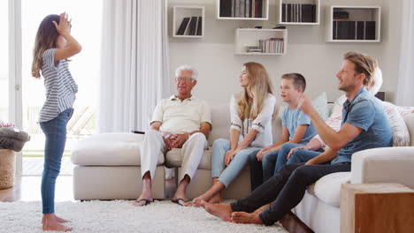 multi generation family sitting on sofa at home playing charades