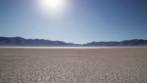 dry, cracked desert landscape with mountains in the background