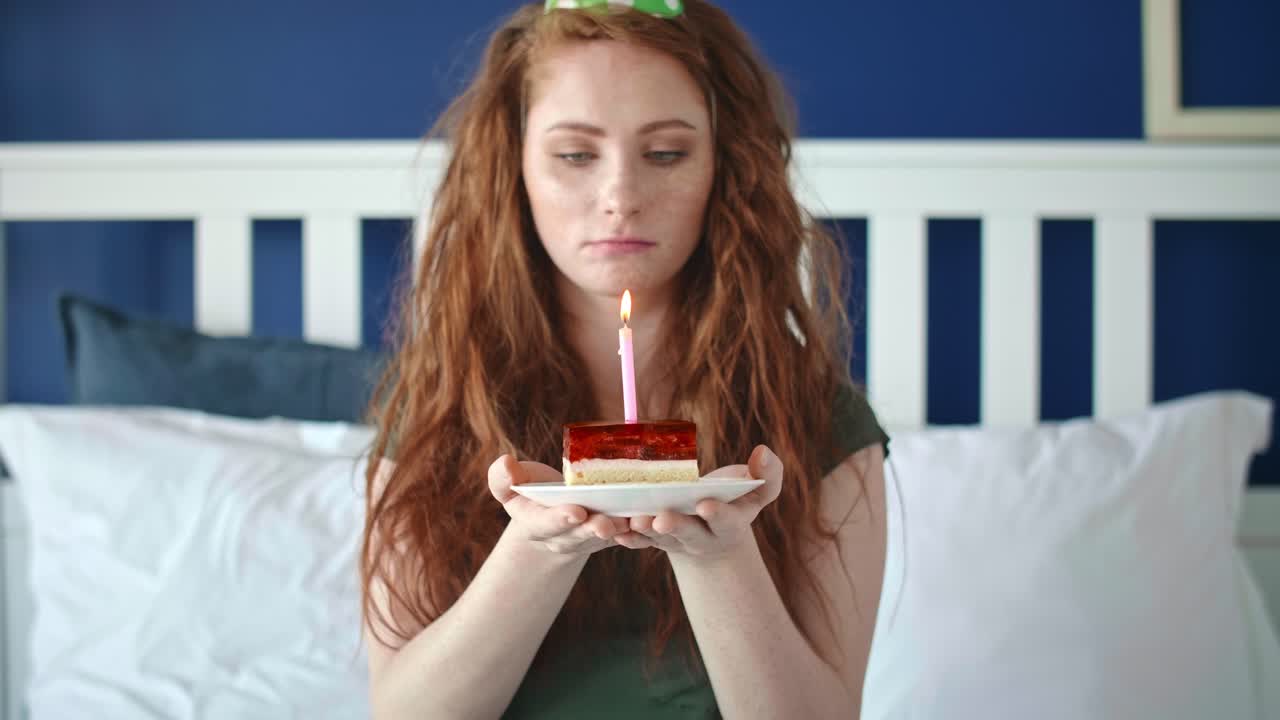 Video con zoom indietro di una donna triste che soffia una candela di compleanno.