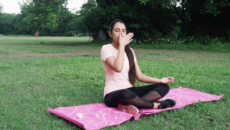 Teenage-Young-Indian-girl-doing-Indian-yoga-Pranayam-and-meditation-on-ground-at-morning-sunrise,-close-up-shot