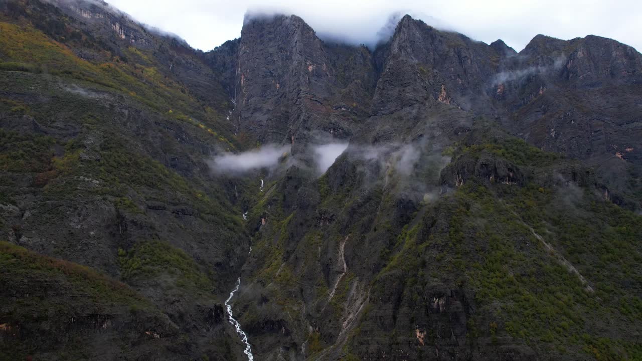 espectacular panorama montañoso con picos rocosos cubiertos de niebla y nubes, el agua de los arroyos fluye rápidamente