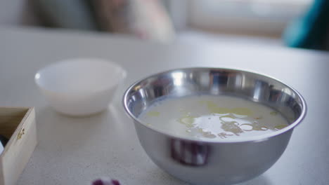 primer plano de la leche y el aceite en el cuenco de metal para la preparación de la masa