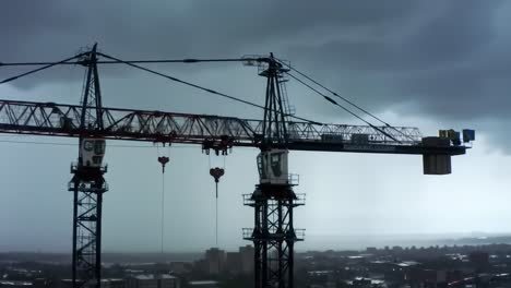 a dramatic view of construction cranes against a stormy sky: industrial equipment amidst dark clouds and rain, capturing the essence of urban development