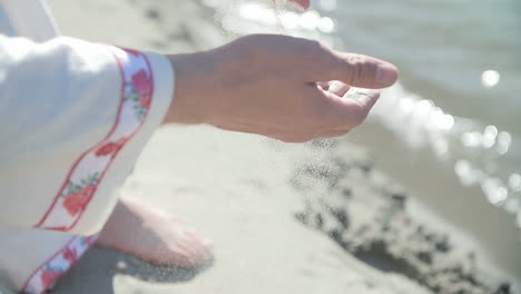 woman sitting on beach,  touching sand
