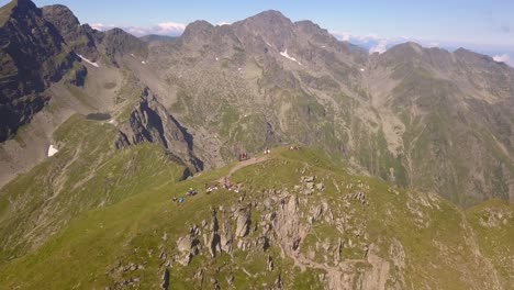 drone orbiting high over remote mountain peak with hikers and backpackers on summit