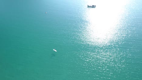 Aéreo,-De-Arriba-Hacia-Abajo,-Ojo-De-Pájaro,-Tiro-De-Drone-De-Un-Hombre-Corriendo-En-Un-Muelle-De-Madera-Y-Gente-Nadando-En-El-Mar-Turquesa,-En-Una-Playa-Paradisíaca,-En-Un-Día-Soleado,-En-Koh-Kood,-Tailandia,-Asia